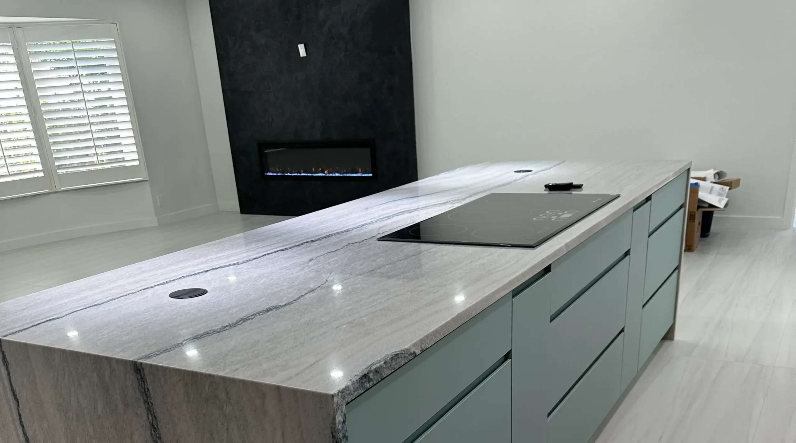 A completed luxury kitchen remodeling project featuring a modern island and built-in fireplace by Delaurentiis Construction in Fort Lauderdale, FL.