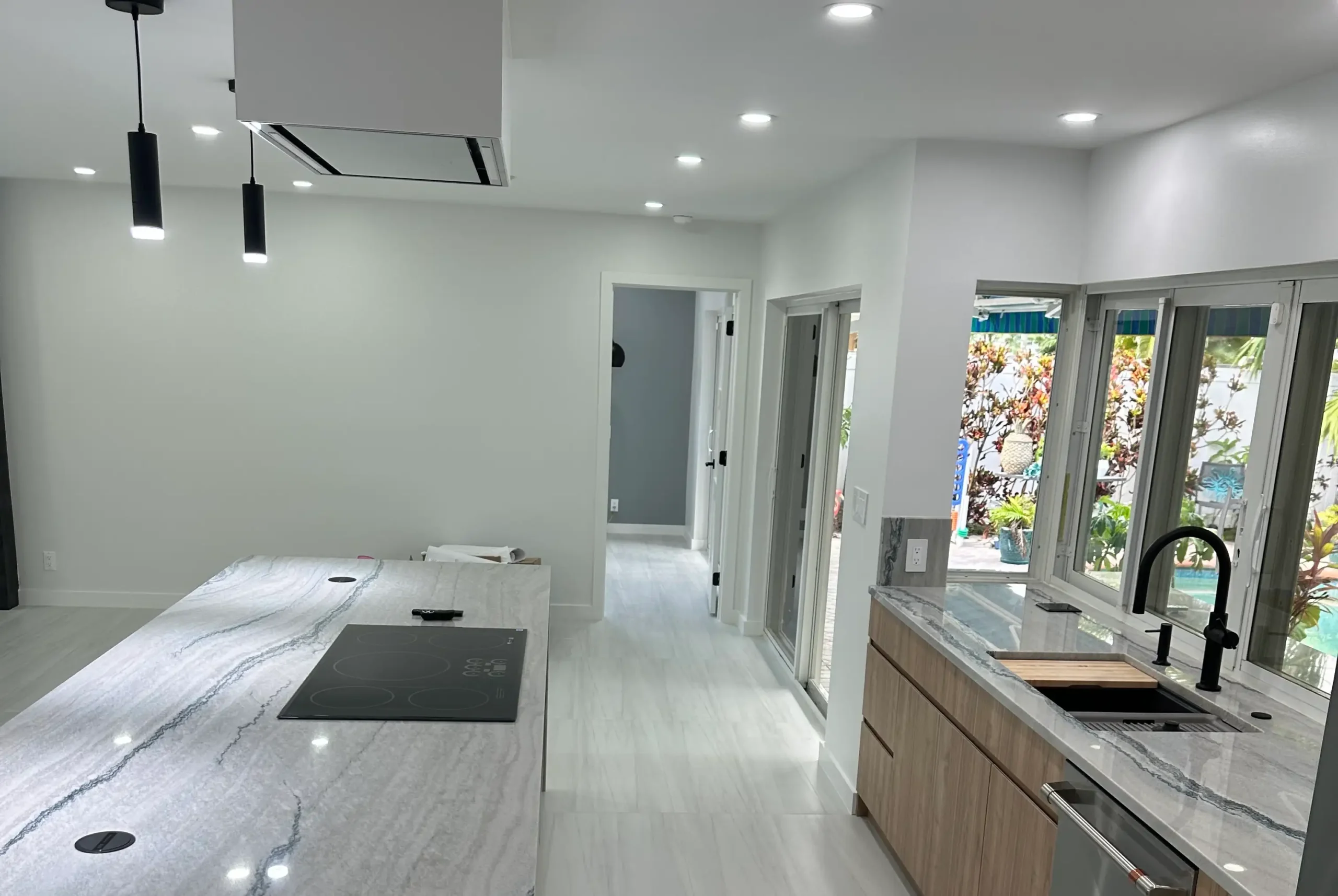 Modern single-story home exterior remodel featuring a metal roof, wood accents, and custom paver walkway.