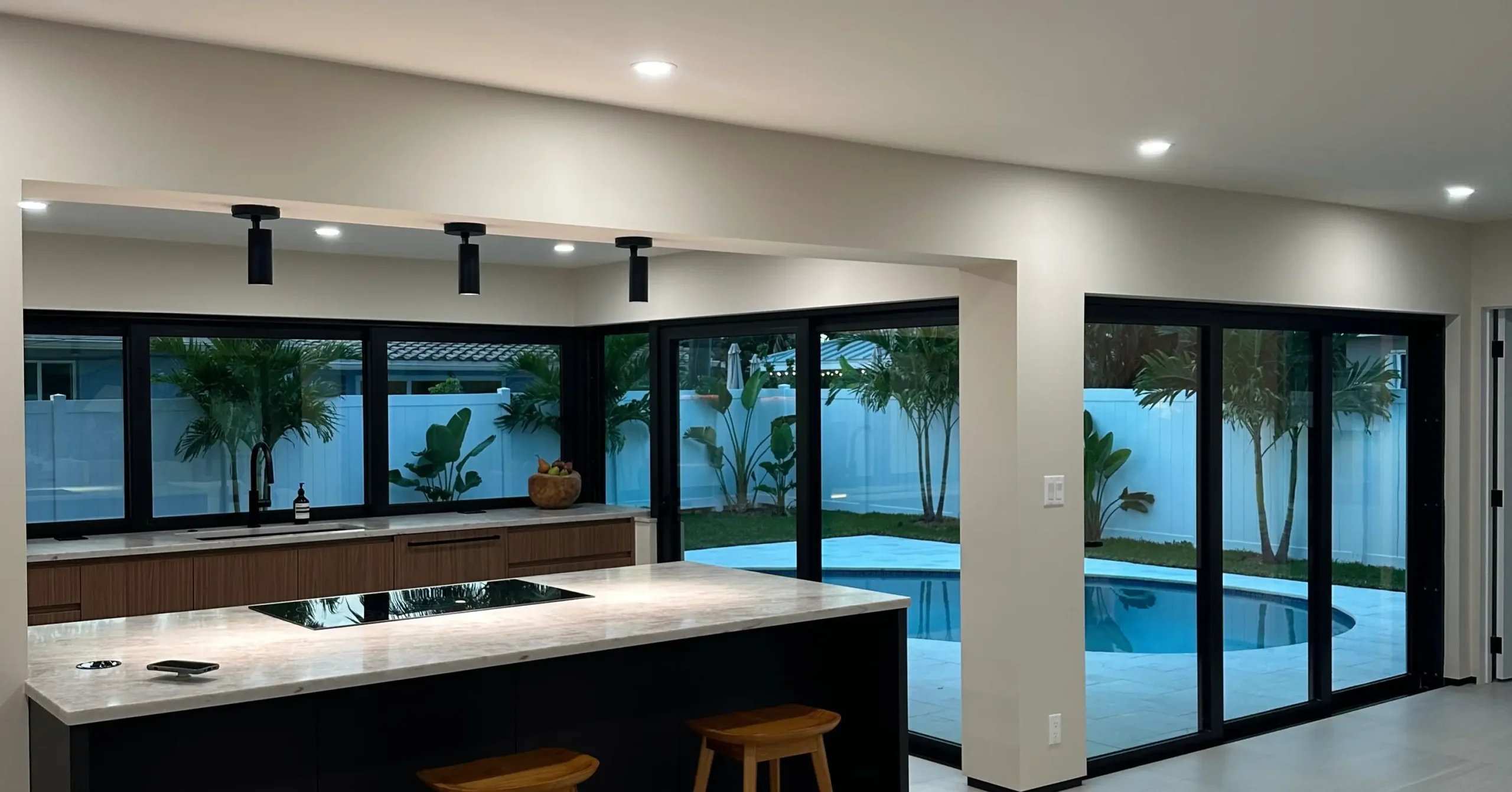 Interior overview of a premium luxury home addition featuring a modern kitchen and pool view by Delaurentiis Construction in Fort Lauderdale, FL.